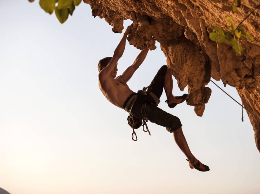 Homme en train de grimper une falaise, symbolisant l’ascension grâce à une bonne accroche marketing