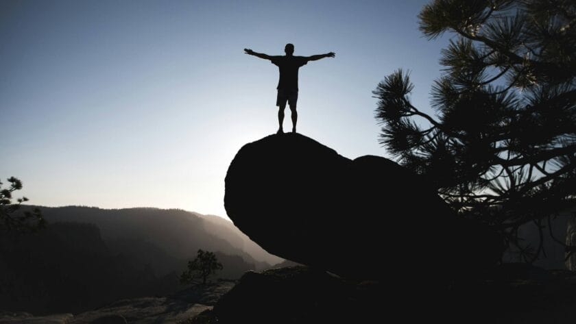 Personne debout sur un rocher, bras ouverts, symbolisant la confiance et la légitimité