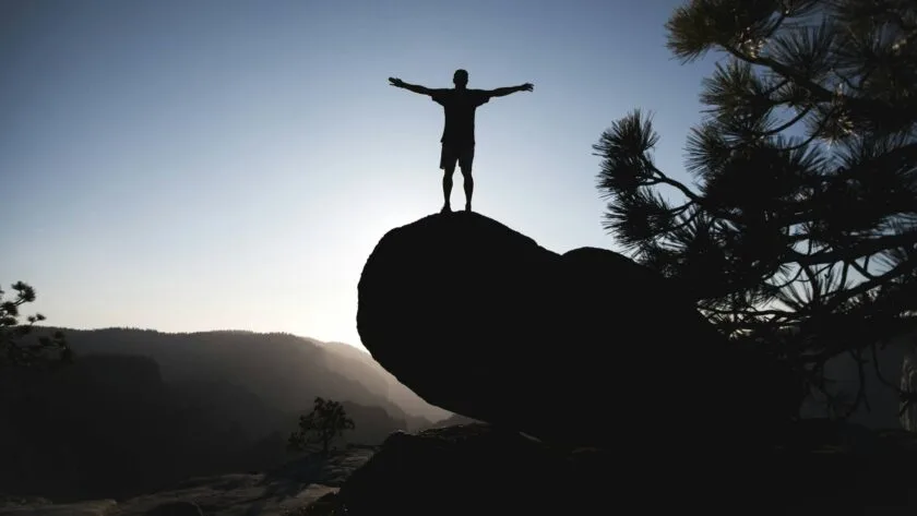 Person standing on a rock, arms open, symbolising confidence and legitimacy