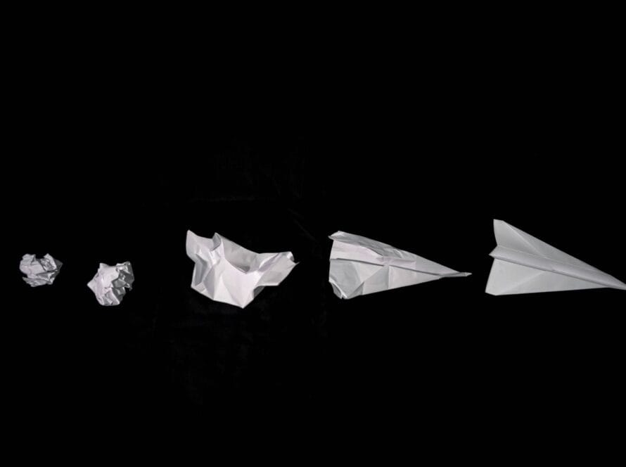 Séquence de feuilles de papier froissées devenant un avion en papier, symbolisant le repositionnement stratégique
